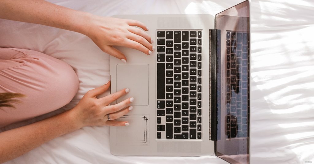 A woman researches the benefits of rhinoplasty on her computer.